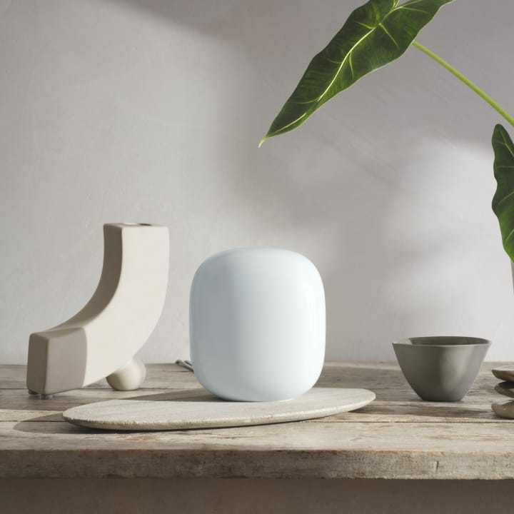 Fog-colored Nest Wifi Pro sits atop a desk in a home-office space.