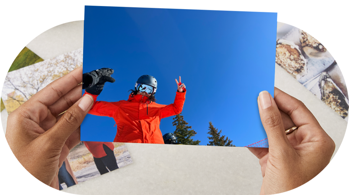A photo print of a skier holding up a peace sign under a blue sky.